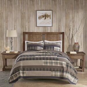 Neutral plaid quilt layered on warm farmhouse style bed