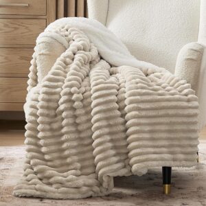 Neutral sherpa throw blanket layered on modern sofa