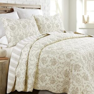 Floral vintage style quilt layered on neutral farmhouse bed