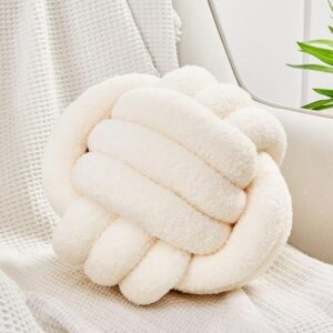 Cream decorative knot throw pillow styled on a cozy neutral chair, perfect for minimalist room design and modern home decor.