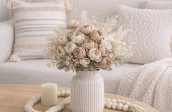 Spring coffee table decor styled with neutral ceramic vase, faux ranunculus flowers, wooden bead garland, and warm wood coffee table in a cozy minimalist living room